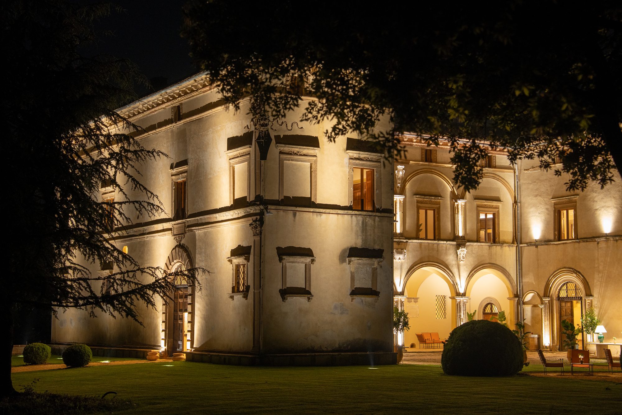 La facciata di Volte Alte vista dal prato, con il loggiato illuminato al tramonto